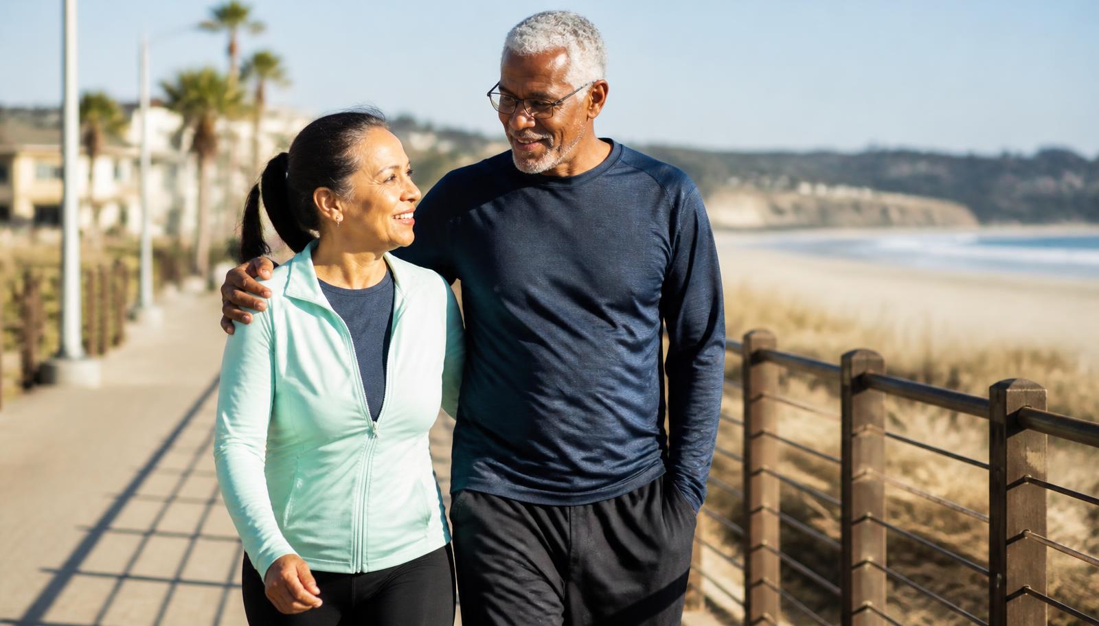 Retired couple walking together on a coastal boardwalk